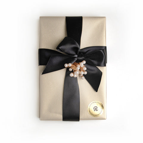 1 lb fancy wrapped box. Gold, and white pin-stripped wrapping paper. Tied with a black satin ribbon and white decorative piece