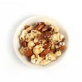 A mix of buttery rich, caramel coated pecans, almonds and fresh popcorn, packaged in a paper bag with a clear window.